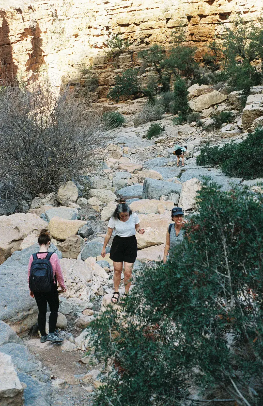 Guests hiking between boulders in a sandstone canyon