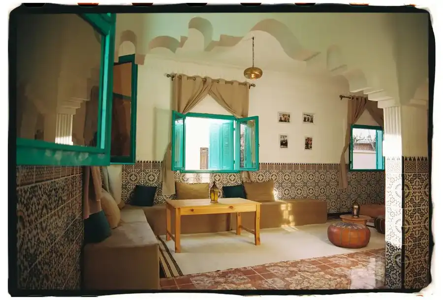 Salon with zellige walls, turquoise windows and beige sofas