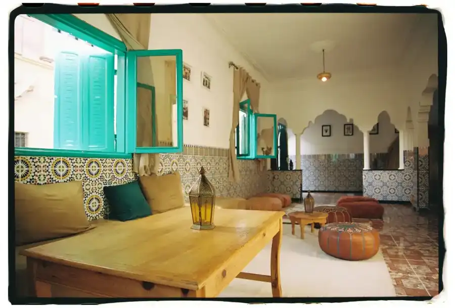 Salon with turquoise window, zellige walls and Moroccan lantern