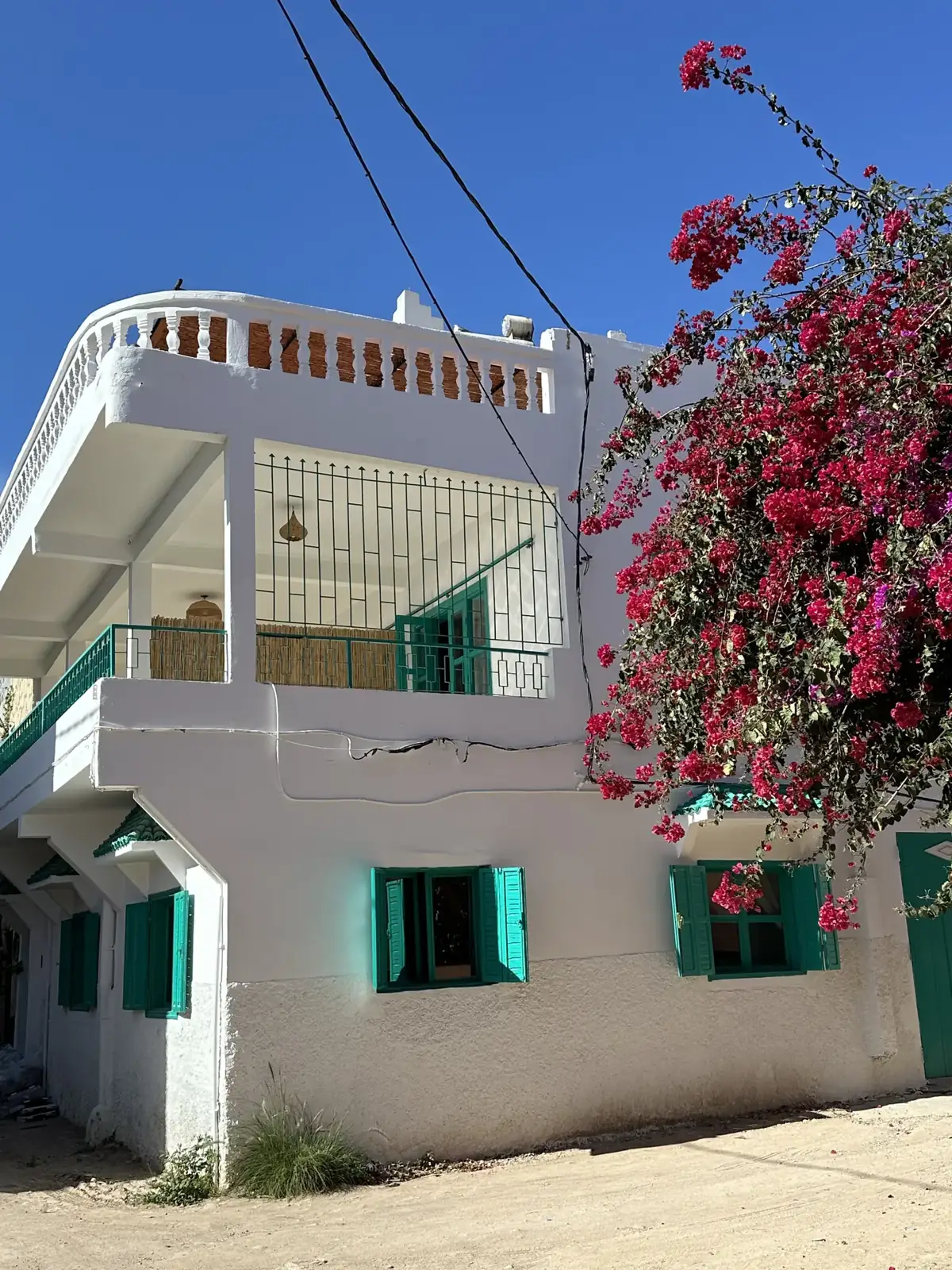 Whitewashed riad with turquoise shutters and bougainvillea in Tamraght