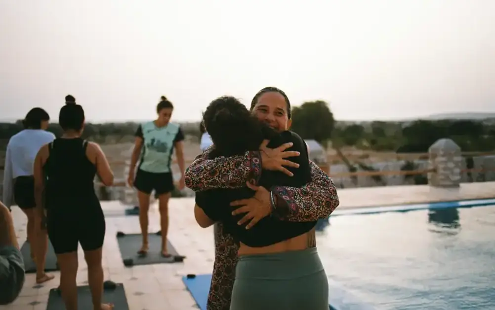 Guests hugging after a sunrise session by the pool
