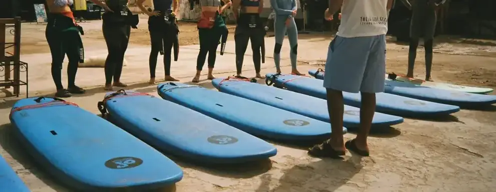 Surf lesson group with soft-top boards lined up on the beach