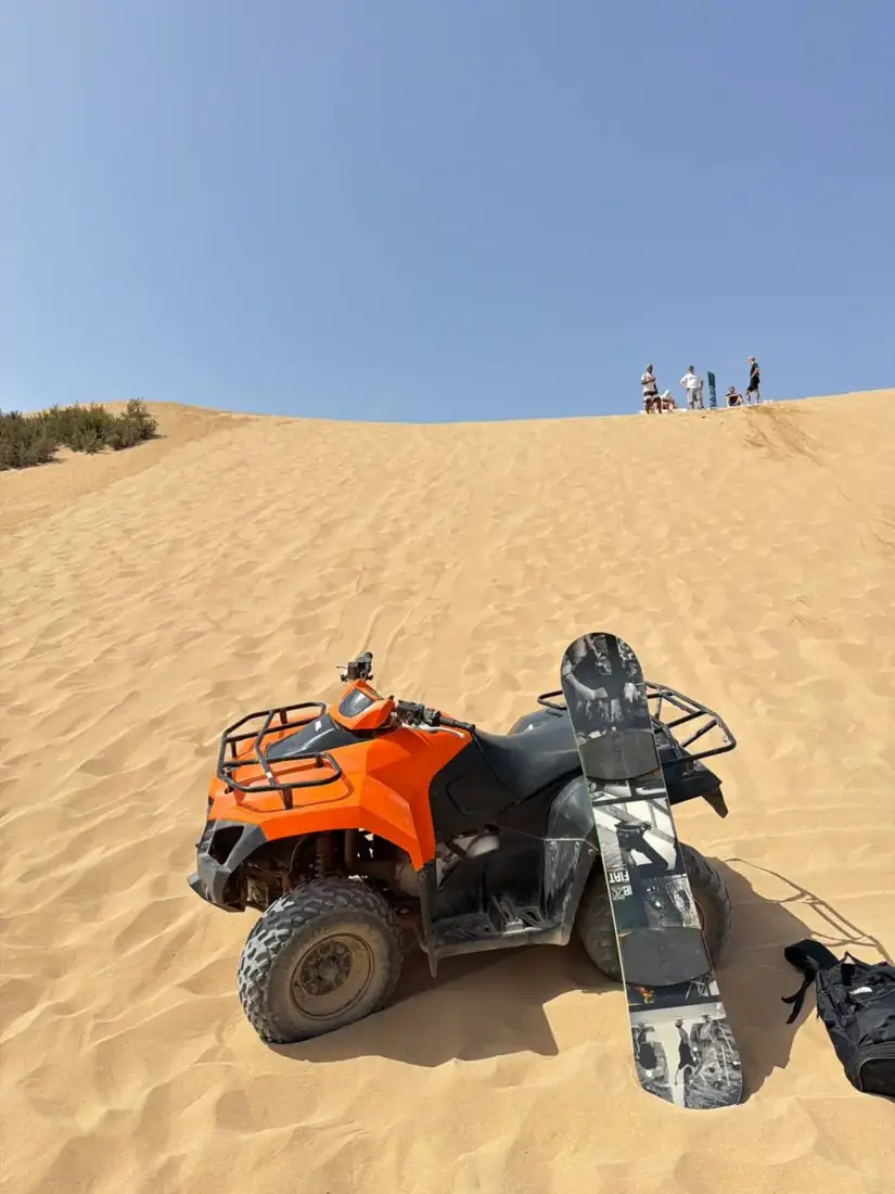 Quad bike and sandboard on a golden dune