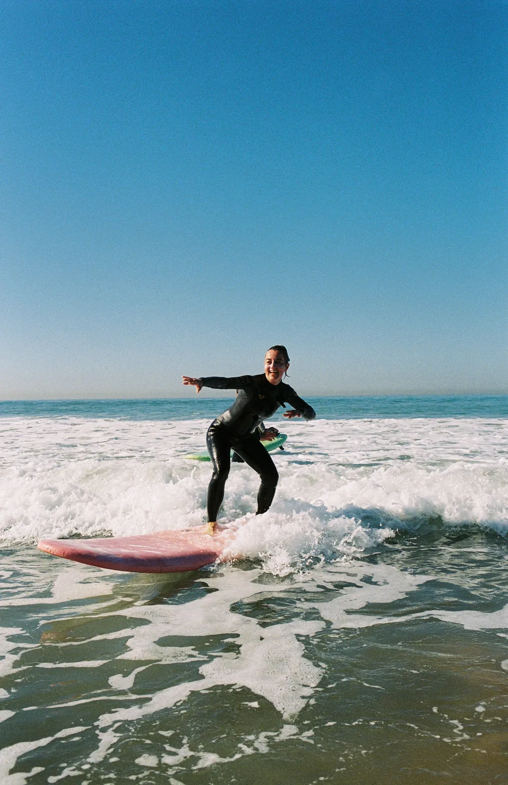 Smiling surfer riding the white water on a pink soft-top