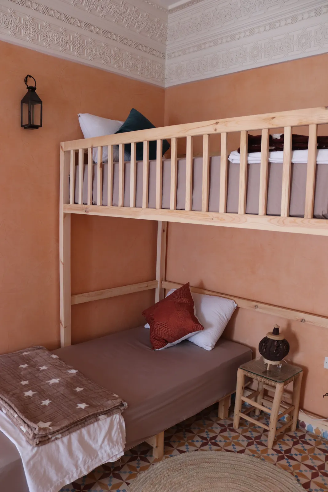 Wooden bunk bed in a shared room with peach walls