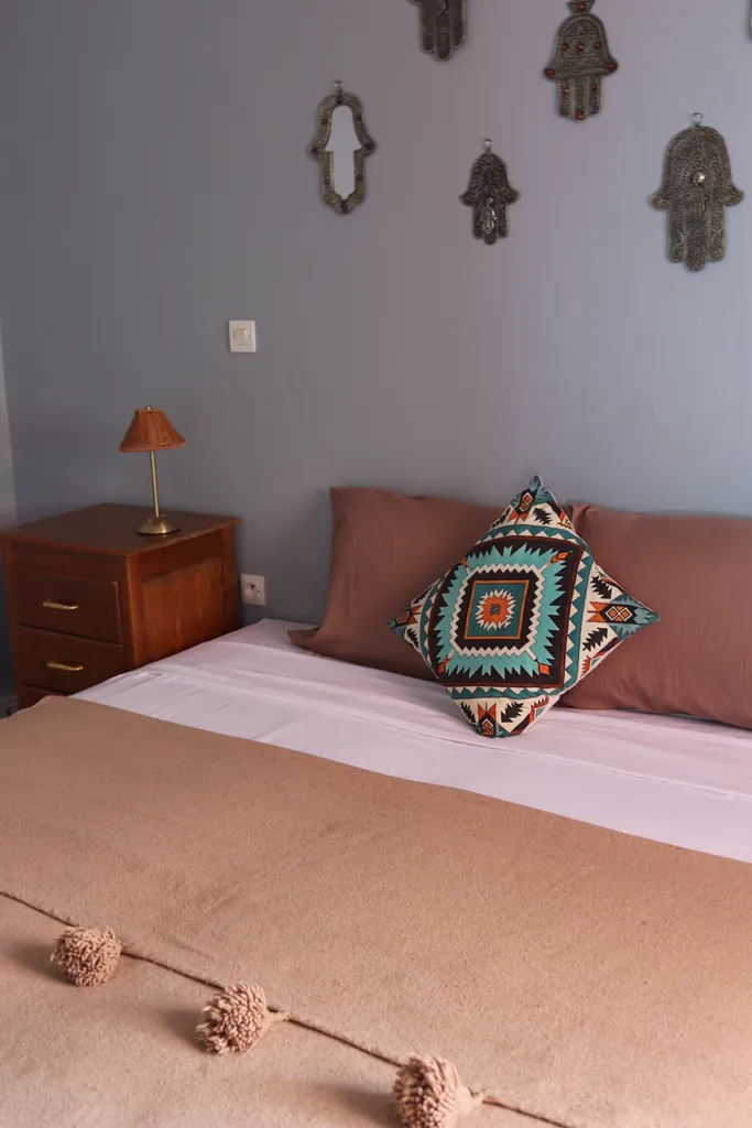 Double bed with a pompom blanket and a patterned cushion