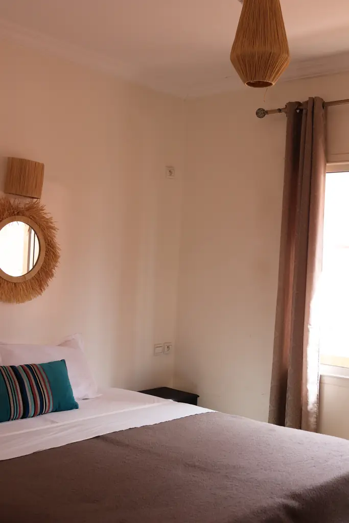 Tweepersoonsbed onder een zonnespiegel van raffia
