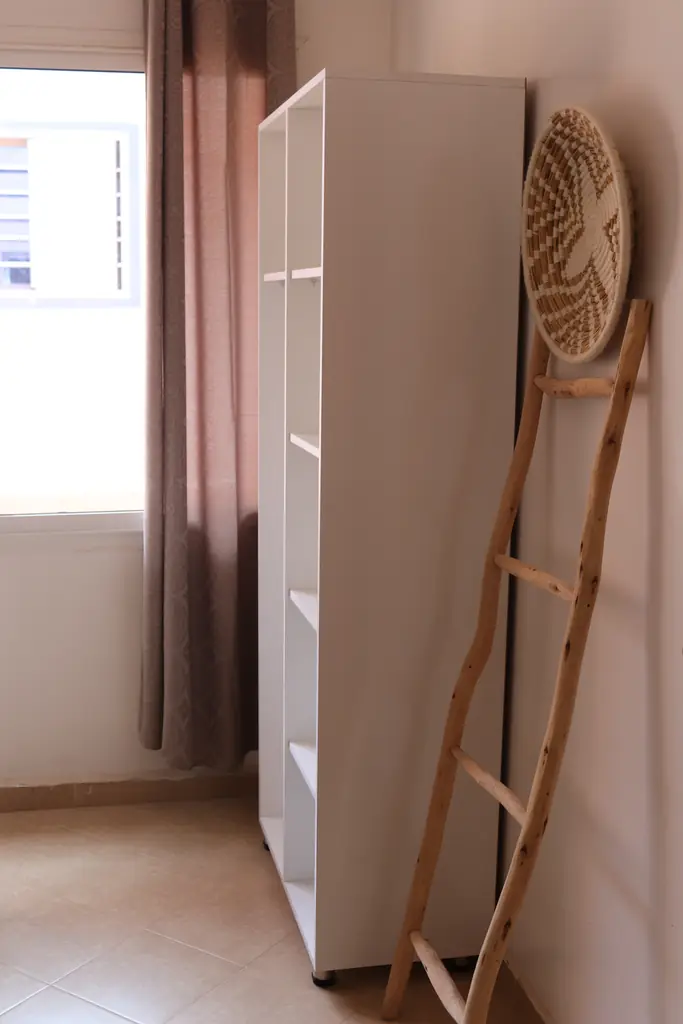 Witte kledingkast en een houten ladder met een gevlochten mand