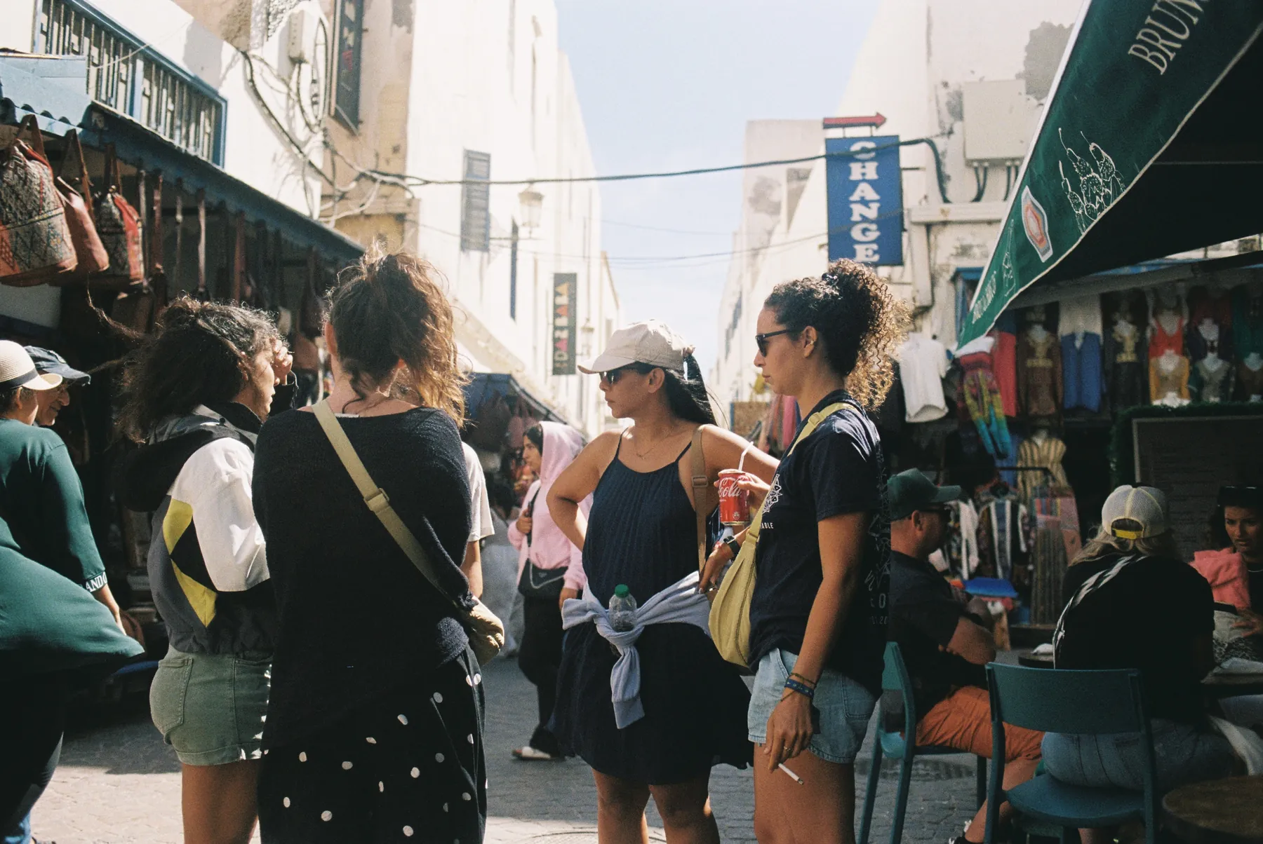 Friends exploring a busy medina street with leather bags and colourful shops