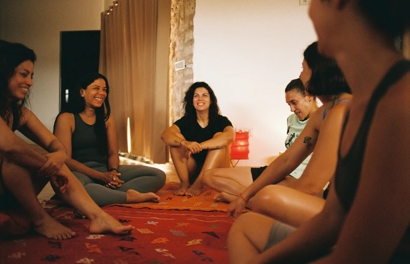 Guests sitting in a circle on a Berber rug, laughing
