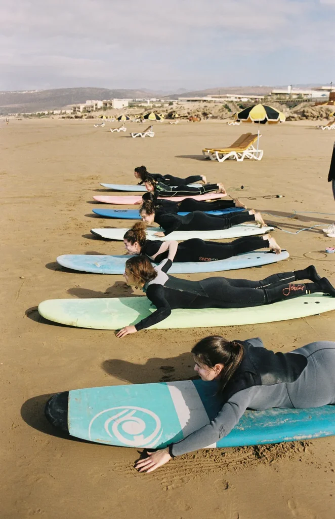 Surf lesson group practising pop-ups on the sand