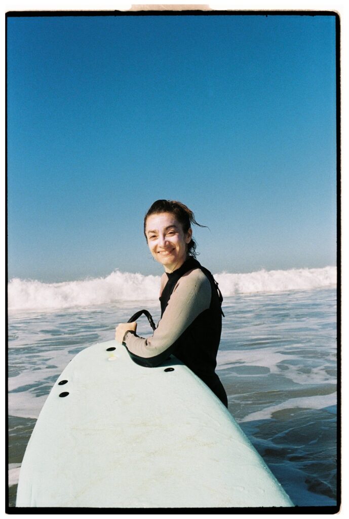 Un surfeur débutant pratiquant la bonne technique de pagaie sur une planche dans les vagues d'écume à la plage de Tamraght.