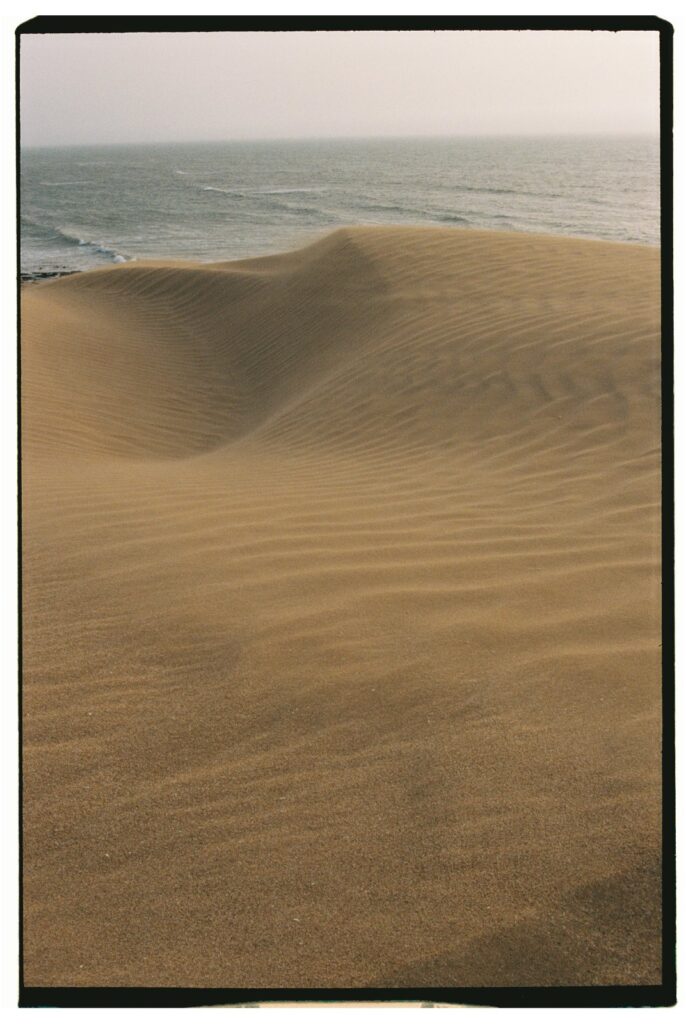 Dunes de sable doré de Timlalin rencontrant l'océan Atlantique sous un ciel de coucher de soleil