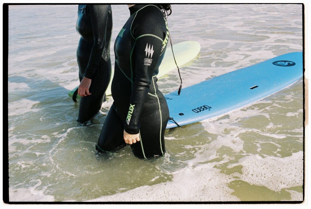 Moniteurs et élèves de surf marchant sur la plage avec des planches soft top en novembre